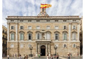 דגלי קטלוניה וספרד מעל בניין Generalitat בכיכר Plaça de Sant Jaume בברצלונה (צילום: לא צויין צלם, הועלה ל‑Wikimedia Commons, רישיון CC BY‑SA או Public Domain)